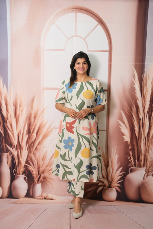 Woman in a floral dress standing in front of a decorative wall with vases and plants.