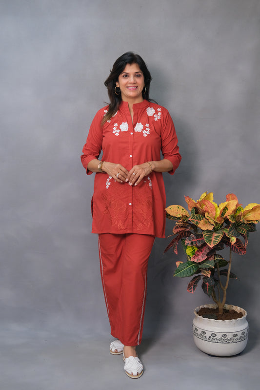 Woman in a red outfit standing next to a potted plant against a gray background