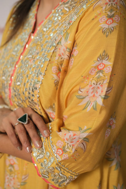 Yellow floral dress with intricate embroidery and a ring on a finger.