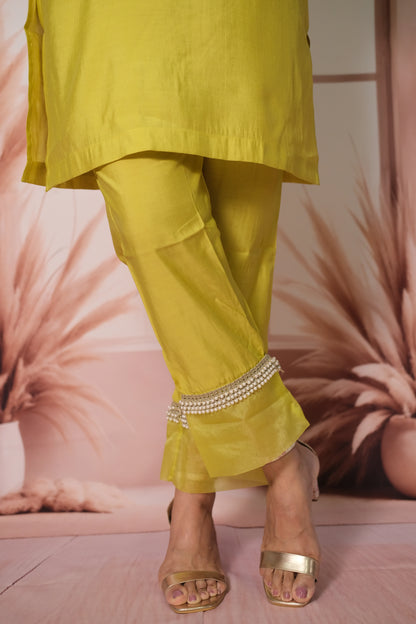 Person wearing a bright yellow outfit with embellished pants against a pink floral background