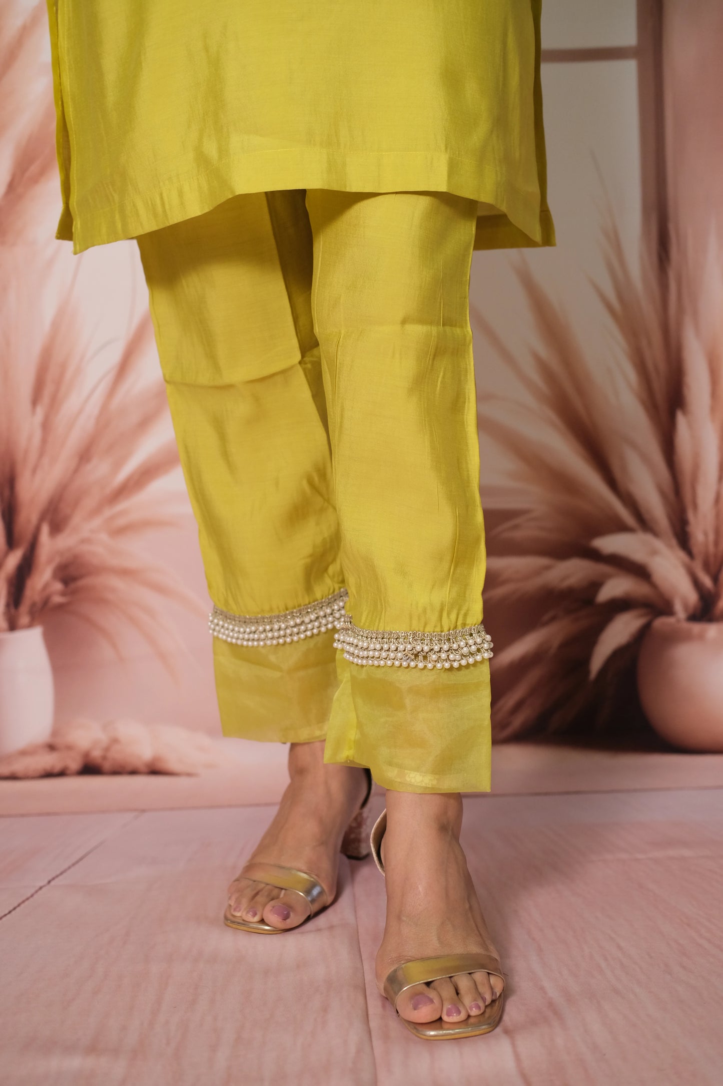 Yellow outfit with embellished pants on a pink background