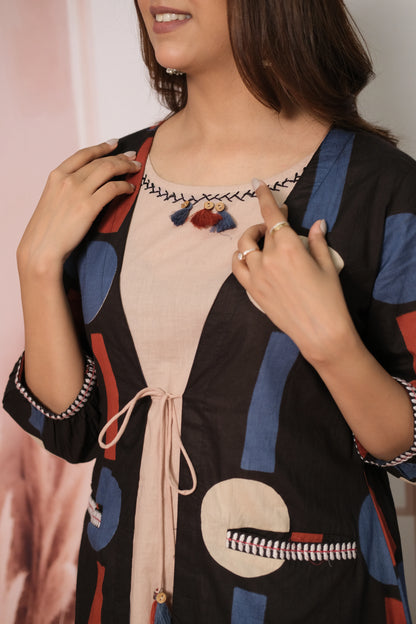 Woman wearing a black cardigan with colorful patterns over a pink top.